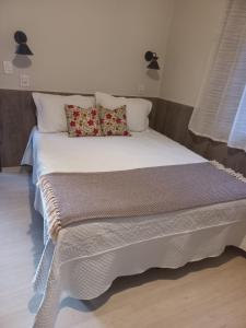 a bed with white sheets and pillows in a room at Recanto Caminho das Águas in Caxambu +47 photos