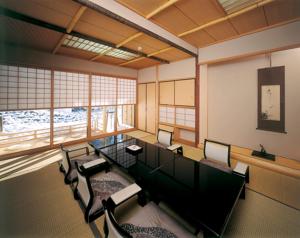 Nishiyama Onsen Keiunkan في Hayakawa: غرفة كبيرة فيها طاولة وكراسي