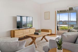 Blue Cottage Bruny Island في Alonnah: غرفة معيشة مع تلفزيون وطاولة وكراسي