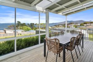 a porch with a table and chairs and windows at Blue Cottage Bruny Island in Alonnah