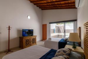 a bedroom with two beds and a tv and a window at Finca Hotel Casa Bela in Santa Fe de Antioquia