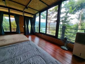 Baanhatsompaen homestay في رانونغ: غرفة نوم مع سرير في غرفة مع نوافذ كبيرة