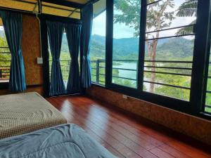 - une chambre avec un lit et de grandes fenêtres avec vue dans l'établissement Baanhatsompaen homestay, à Ranong
