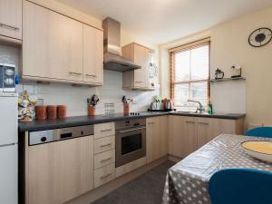 a kitchen with wooden cabinets and a sink and a table at Lower Street 10 Flat 3 in Dartmouth