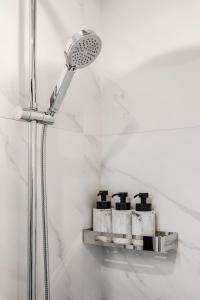 eine Dusche mit Duschkopf und ein Regal mit Pflegeprodukten in der Unterkunft Stylish Apartment in Zverynas in Vilnius