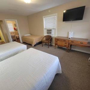 Cette chambre comprend deux lits, un bureau et une télévision. dans l'établissement Early American Motel, à Aurora