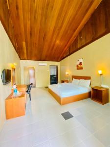 una grande camera da letto con letto e soffitto in legno di Landcons Hotel & Resort a Pantai Cenang