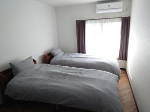 two beds in a bedroom with a window at Albany inn Shirahama アルバニーイン白浜 in Shirahama