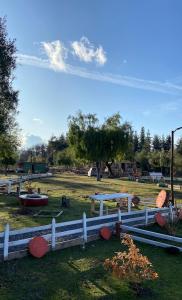 una cerca blanca frente a un campo con árboles en Cabañas Vista Hermosa Radal 7 Tazas en El Torreón