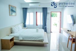 1 dormitorio con cama blanca y escritorio en สราญรัตน์รีสอร์ท en Ban Noen Makok