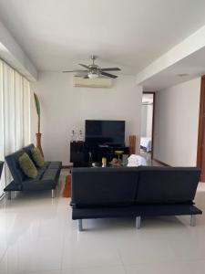 uma sala de estar com um sofá preto e uma televisão em Apartamento Condominio Zazue Santa Marta em Santa Marta