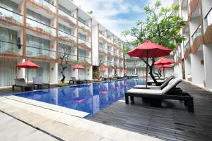 a hotel with a swimming pool and red umbrellas at The Bene Hotel in Kuta