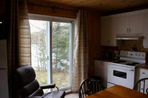 a kitchen with a large window and a table with chairs at Chalet Au Bord du St-Maurice in La Tuque