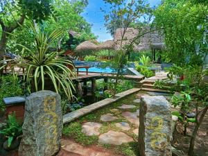 un jardín con piscina y algunas rocas y árboles en Habarana Tree House Ambasewana Resort en Habarana