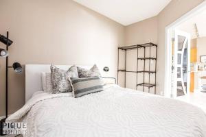 - une chambre avec un lit blanc et des oreillers dans l'établissement Luxury Downtown Suite, River Valley View, Patio & BBQ, Sleeps 4, à Edmonton