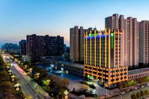 Holiday Inn Express Xinji City Center, an IHG Hotel في Xinji: مبنى طويل وبه أضواء عليه في مدينة