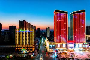 Holiday Inn Express Xinji City Center, an IHG Hotel في Xinji: أفق المدينة في الليل مع الأضواء الحمراء