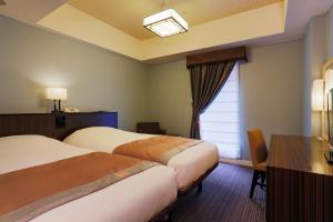 a hotel room with two beds and a window at Hotel Monterey Hanzomon in Tokyo