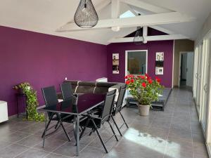 uma sala de jantar com paredes roxas e uma mesa e cadeiras em Le SPA de l Albizia em Cessieu