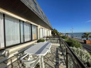 a white table on a balcony with the ocean at Appartement Duplex en Front de Mer avec Terrasse – Accès Direct Plage – 2 Chambres + Cabine - FR-1-361-456 in Saint-Pair-sur-Mer