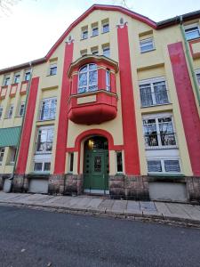 un edificio amarillo y rojo con una puerta verde en Galerie-Ferienwohnung "Im Schindlershof" - zentral und ruhig, en Eibenstock