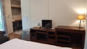 a room with a desk with a television and a bed at ที รีสอร์ท T Resort Suphanburi in Ban Noi