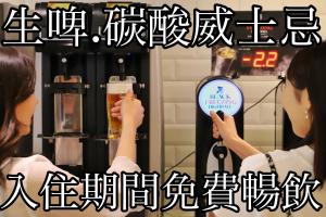 Okinawa Hinode Resort and Hot Spring Hotel في ناها: امرأة تمسك كأس من البيرة أمام آلة