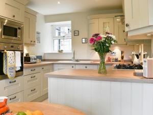 a kitchen with a vase of flowers on a counter at Rooftops - Uk34065 in Grassington