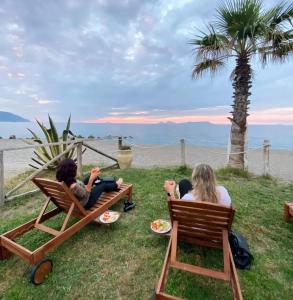 dos mujeres sentadas en sillas en el césped cerca de la playa en on the beach, en Gioiosa Marea