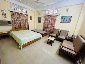 a bedroom with a bed and two chairs in it at The Choudhury Manor Homestay in Guwahati