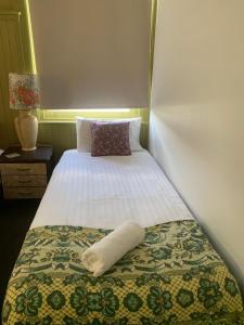 a bed in a room with a white pillow on it at Vine Valley Inn in Cessnock