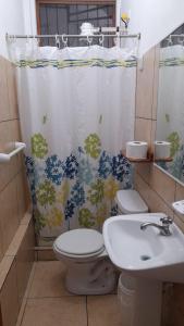 a bathroom with a toilet and a sink and a shower curtain at El Paraiso in Puerto Ayora