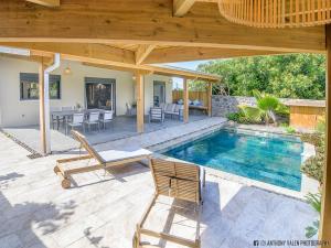 a patio with a swimming pool and a wooden pergola at Villa Fleur de Jade in Saint-Louis