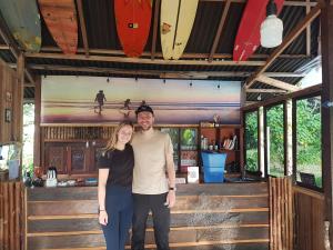Un uomo e una donna in piedi in una stanza con tavole da surf di Amban Beach House a Manokwari