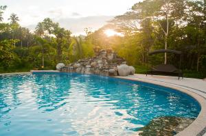 a swimming pool with a waterfall in a backyard at Loboc River Resort in Loboc