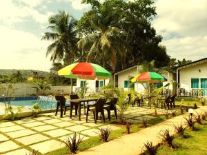 un patio con mesas y sombrillas junto a una piscina en White Truffle Resort, Arambol en Arambol
