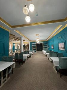 una sala da pranzo con pareti blu e tavoli e sedie bianchi di Гостиница Селена a Qyzylorda