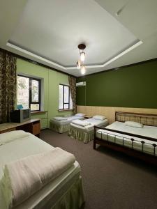 three beds in a room with green walls at Гостиница Селена in Qyzylorda