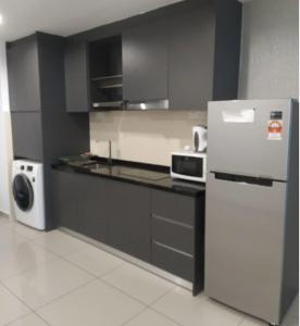 eine Küche mit einem Kühlschrank und einer Mikrowelle in der Unterkunft Encorp Marina Suites near Legoland in Nusajaya