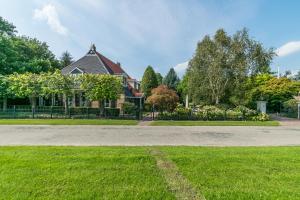 a house with a grass yard and a driveway at Logies De Houtdijk in Harich