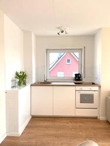 una cocina con armarios blancos y una ventana en FeWo small Penthouse Lake of Constance with large terrace, en Friedrichshafen