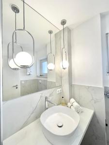 Baño blanco con lavabo y 2 luces en FeWo small Penthouse Lake of Constance with large terrace, en Friedrichshafen