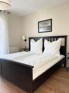 1 dormitorio con 1 cama grande con sábanas y almohadas blancas en FeWo small Penthouse Lake of Constance with large terrace, en Friedrichshafen