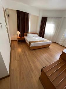 a bedroom with a large bed and wooden floors at Kawan Hotel in Sibu