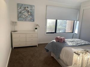 a bedroom with a bed with two pink towels on it at Kathy's Place in Torquay