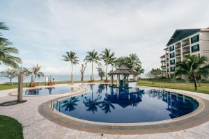 a resort pool with a gazebo and palm trees at Borneo Beach Villas in Kota Kinabalu