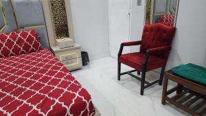 a bedroom with a red bed and a red chair at Karachi Guest House - Gulshan in Karachi