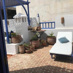 a patio with potted plants and a white bench at Riad le Consulat - Riad privé avec services in Essaouira