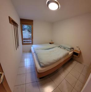 Schlafzimmer mit einem Bett und einem Fenster in der Unterkunft Apartment Grillon in Anzère