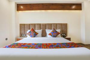 - une chambre avec un grand lit blanc et des oreillers colorés dans l'établissement FabHotel Golf Inn Golf Course Road Gurgaon, à Gurgaon